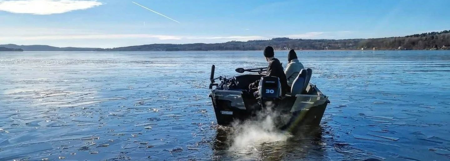 Two friends fishing on alumacraft boat with thin layer of ice