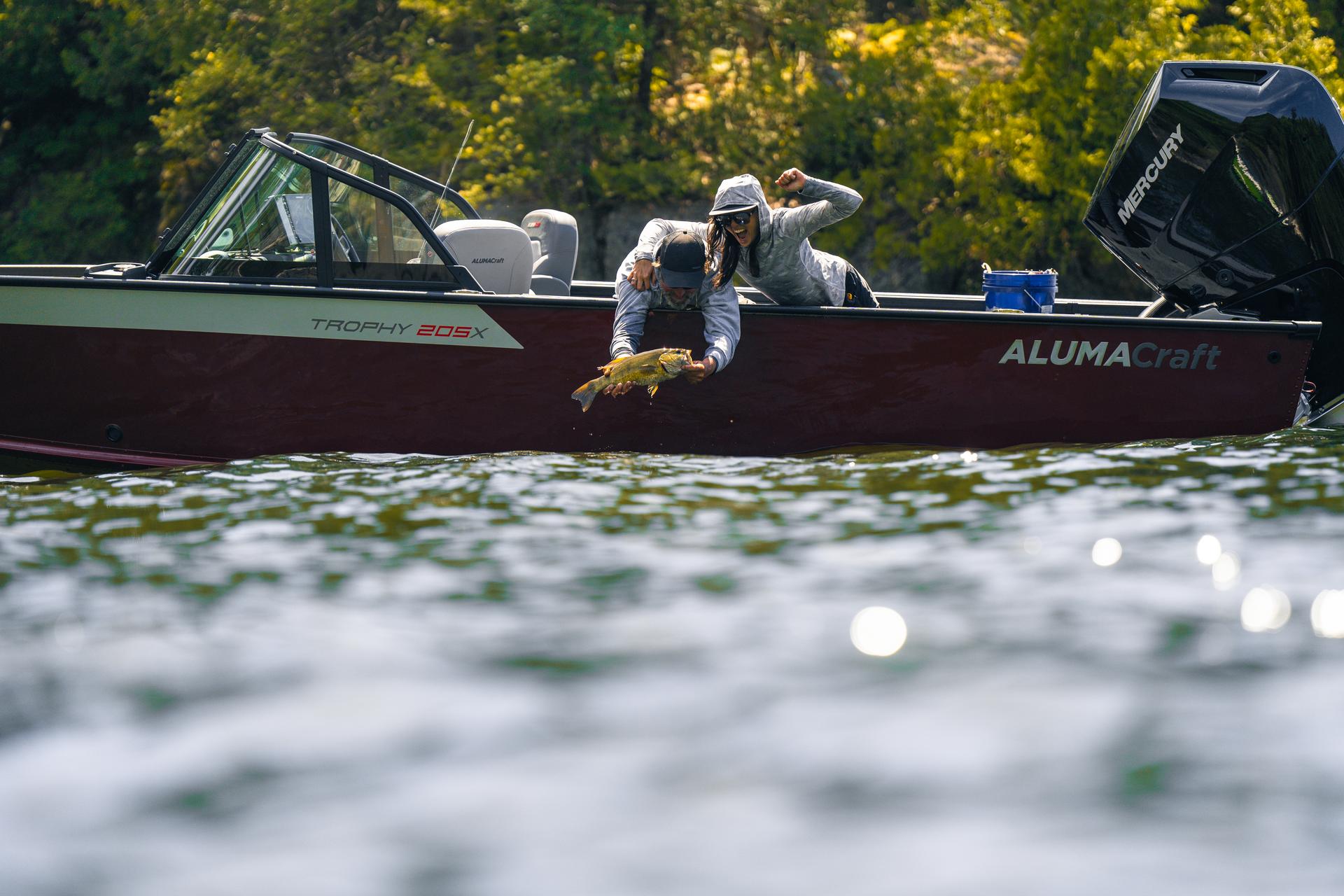 Un pêcheur et une pêcheuse heureux de leur prise, sur un bateau en aluminium Alumacraft