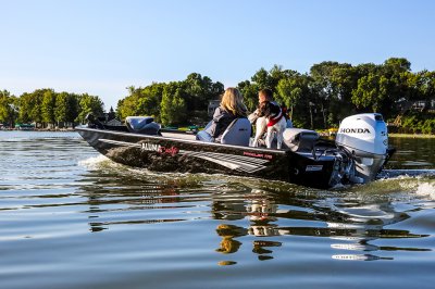 Man, Woman, and Dog Driving A Black Alumacraft 175 Prowler Bass Boat