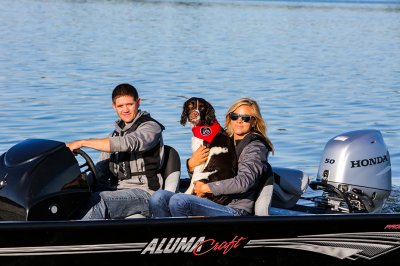 Man, Woman, and Dog Driving A Black Alumacraft 175 Prowler Bass Boat with Honda Motor